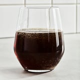 Clear glass filled with dark, bubbly cola. Tasty, carbonated drink with sugar and sweeteners.