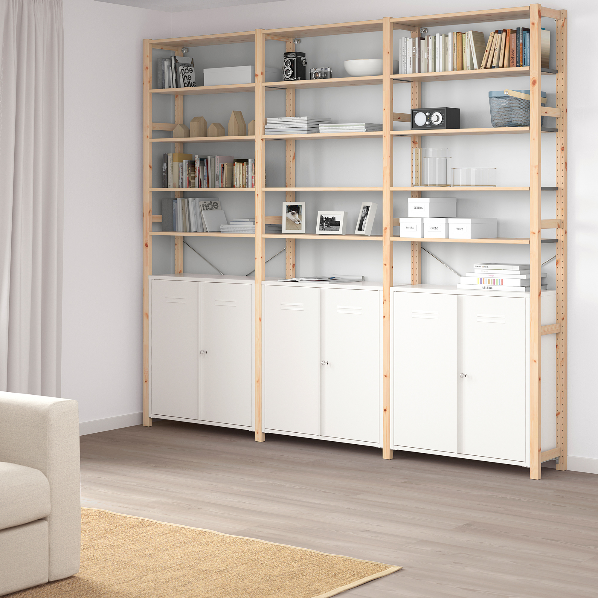 IVAR storage system: tall wooden bookshelves & white cabinets in modern living room, fitting snugly together, with various items like books & decor.