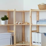 Natural wood IVAR shelves hold books, vases, and plants, providing versatile storage for a room.