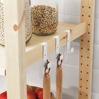 Wooden shelf with white hooks holding jars of pulses and wooden utensils.