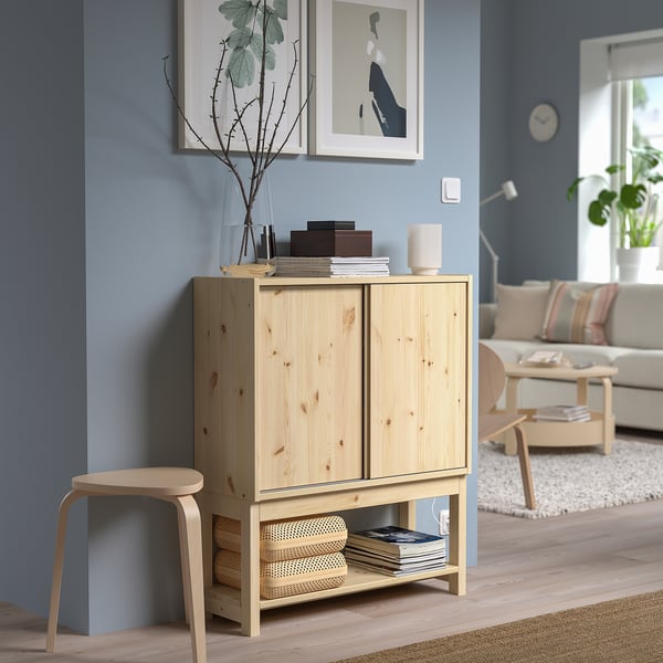 Wooden IVAR cabinet with decor on blue wall.