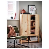 Wooden storage cabinet with open shelves and closed doors, placed near a window. Decorated with a lamp, frames, and plant.