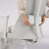 Adjusting lumbar support on ergonomic office chair. Woman securing lumbar support under mesh back.