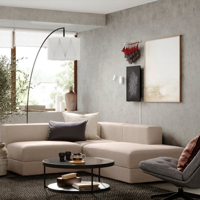 Modern living room with beige sectional sofa, coffee table, grey chair, large window, and abstract artwork.