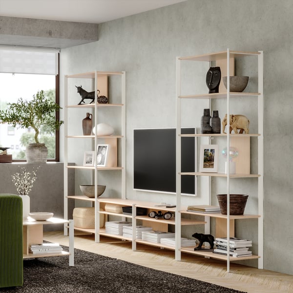 Modern living room with JÄTTESTA shelves holding decor and tv mounted on grey wall.