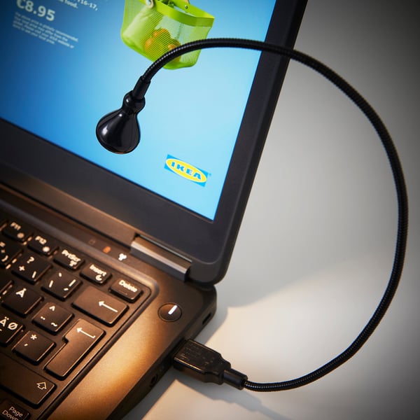 Laptop screen with a black ikea flexi-lamp attached, providing focused illumination.