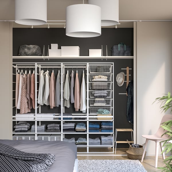 JONAXEL closet with clothes, shelves, baskets, chair, and lights.