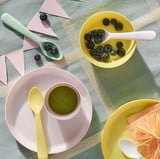 Colorful kids plates and spoons with blueberries and smoothie.