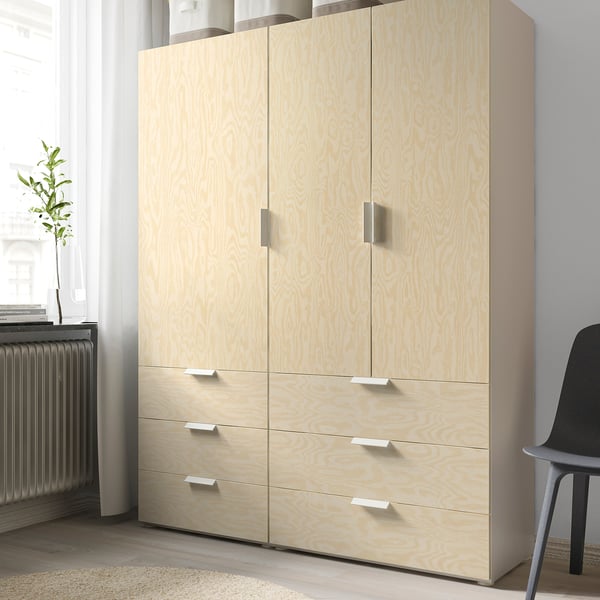 Light wooden storage unit with four drawers and two cabinets, standing against a wall.