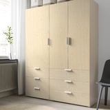 Light wooden storage unit with four drawers and two cabinets, standing against a wall.