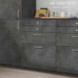 Dark-grey KALHYTTAN kitchen cabinets with concrete texture. Silver handles, four drawers, compact yet spacious.