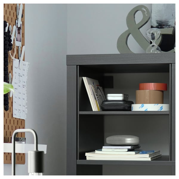 Modern grey shelf unit organized with books, boxes, and a lamp. Wood and metal design with grey finish.