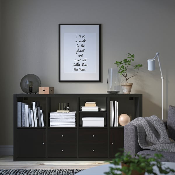 Cozy living room with KALLAX shelf, books, lamp, and plant.