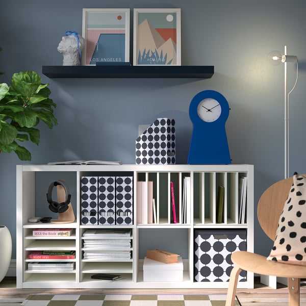 Modern living room with blue wall and KALLAX shelves holding books and decor.