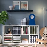 Modern living room with blue wall and KALLAX shelves holding books and decor.