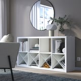 White KALLAX shelf with books, lamps, plants. Large vs chair, mirror wall.