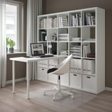 Home office setup: KALLAX shelf unit, white, with open & closed storage, desk on top, laptop, chair, plant.