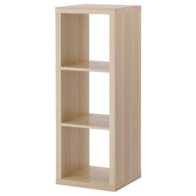 The KALLAX shelving unit is light brown, made of particleboard with a rectangular shape and clean, minimalist design.