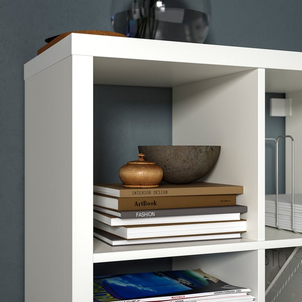 White KALLAX bookshelf with books, bowl, and vase; modern, minimalist design.