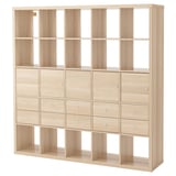A light-colored wooden KALLAX shelving unit with multiple drawers and open compartments.
