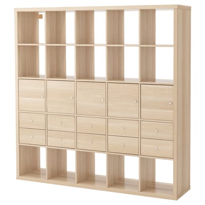 A light-colored wooden KALLAX shelving unit with multiple drawers and open compartments.