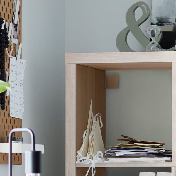 Wooden KALLAX shelves with paper and decorations, standing against a blue wall.
