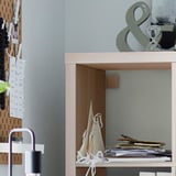 Wooden KALLAX shelves with paper and decorations, standing against a blue wall.