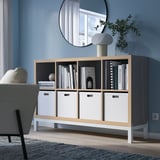 KALLAX shelving unit in light wood and white with books and lamp.