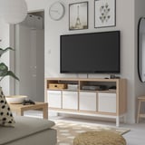 Minimalist tv room with KALLAX tv bench, flat-screen tv, gaming accessories, books, gray sofa, rug, wall art, clock, coffee table, and mirror.