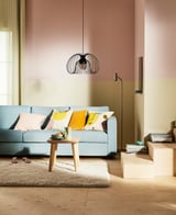 Modern living room with a blue sofa, colorful pillows, wooden table, shaggy rug, and a hanging KALLFRONT lamp.