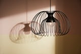 Two modern hanging lamps with black wireframe shades cast intricate shadows.