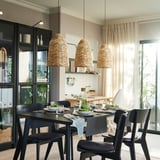 Dining room with KAPPELAND lamps, table setting, dark chairs, glass cabinet, and sheer curtains.