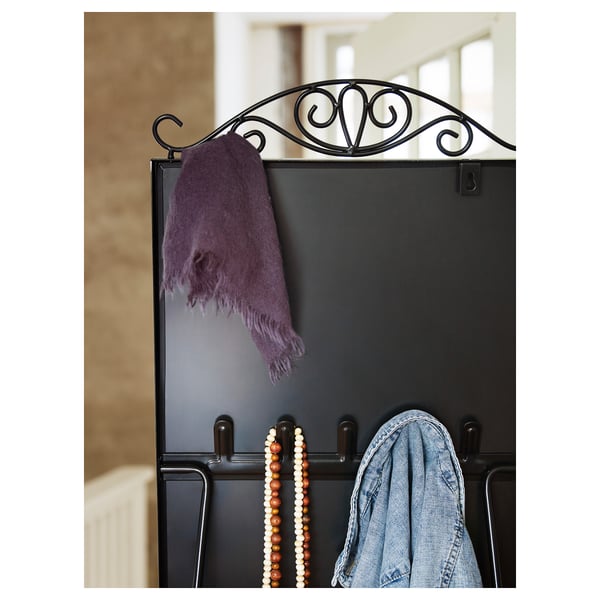 A black mirror with hooks holds a purple scarf, colorful beads, and a denim jacket, reflecting a stylish organization setup.