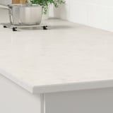 White quartz countertop with stainless pan, plant, and trivet. Durable, stain-resistant, easy to clean.