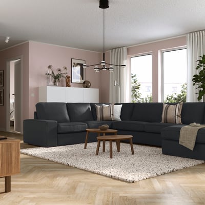 Modern living room with KIVIK sofa, wooden tables, pink walls, natural light, and pendant lamp.