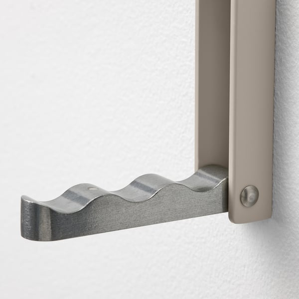 A close-up of a modern, metallic wave-shaped hook mounted on a wall, showing its high-quality design and robust hardware.