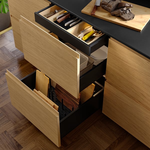 Open kitchen drawer set showing organized utensils, cutlery, and pots, with sleek, dark finish.