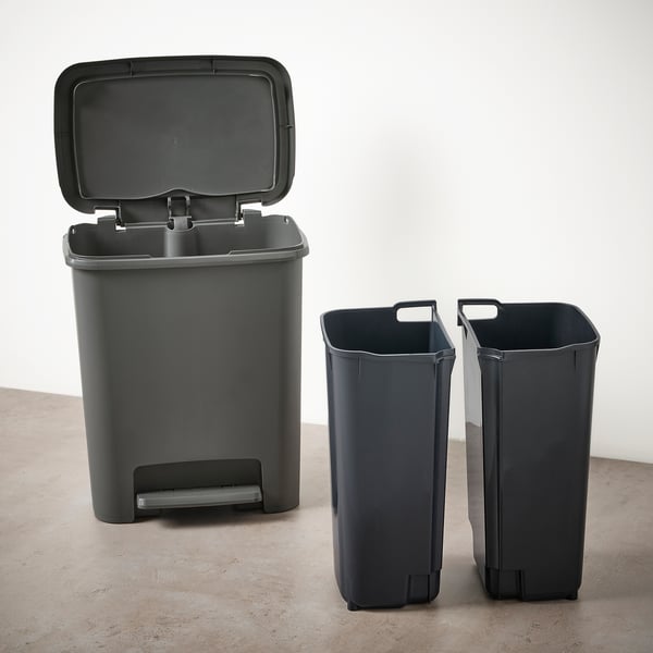 Two grey plastic waste bins with lid open on left, two handle-less bins on right, all standing on beige floor against a white wall.