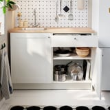 Modern kitchen with white cabinets, wooden counter, stainless sink, and black/white tiles.
