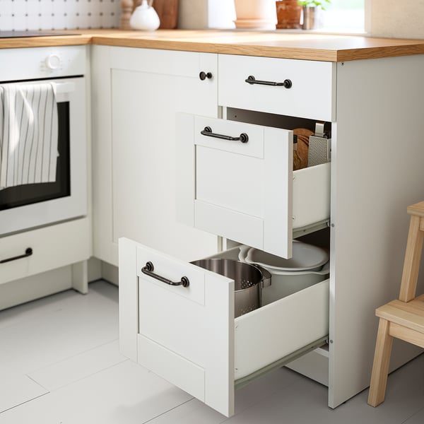 White kitchen cabinet with three open drawers, one holding a metal bin. KNOXHULT organizer for easy access to items.