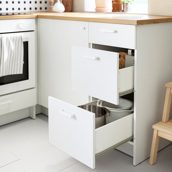 Modern kitchen with KNOXHULT white base cabinet, three open drawers showcasing organized utensils, light wood countertop.