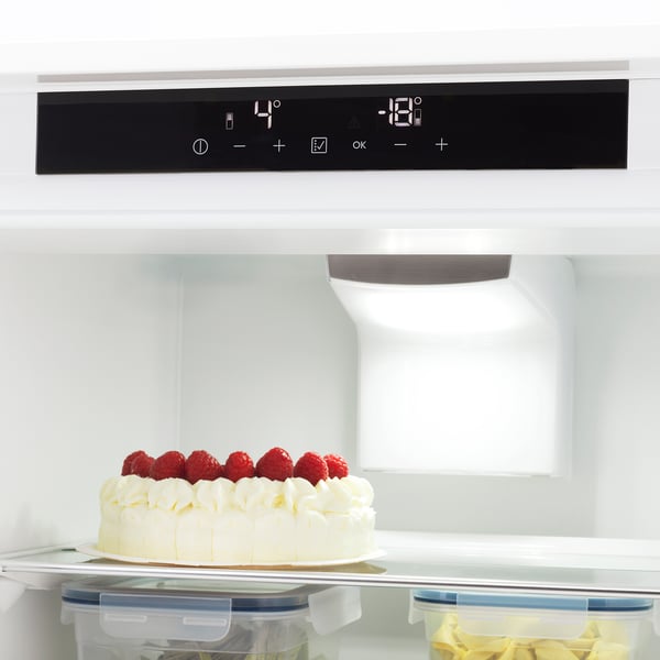 Modern fridge with digital controls and led light. White cheesecake with raspberries, plastic containers shown. Temperature displays at 4°c and -16°c.