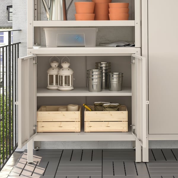 Open storage cabinet with lanterns, pots, and wooden boxes. Perfect for garden tools and cushions.