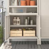 Open storage cabinet with lanterns, pots, and wooden boxes. Perfect for garden tools and cushions.