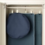 Closed closet with hanging blue textiles, likely storing cushions on rail.