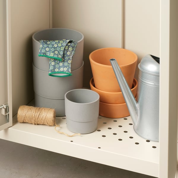 Open shelf with garden tools: two grey pots, twine, two terracotta pots, metal watering can.