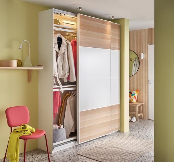 Modern room with yellow walls, wooden floor, open closet, chair with green cloth.