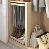 A light wooden closet organizer with hanging pants, shoes, and handbags.