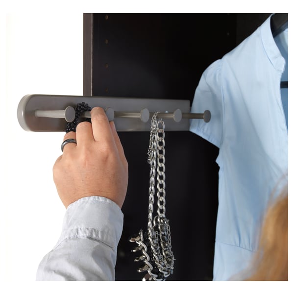 A hand holding a grey multi-use hanger with circular hooks, showcasing its accessory-organizing feature.