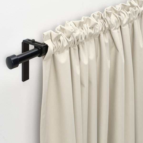 Beige block-out curtains hang on modern brackets, offering light blockage and a sophisticated look.